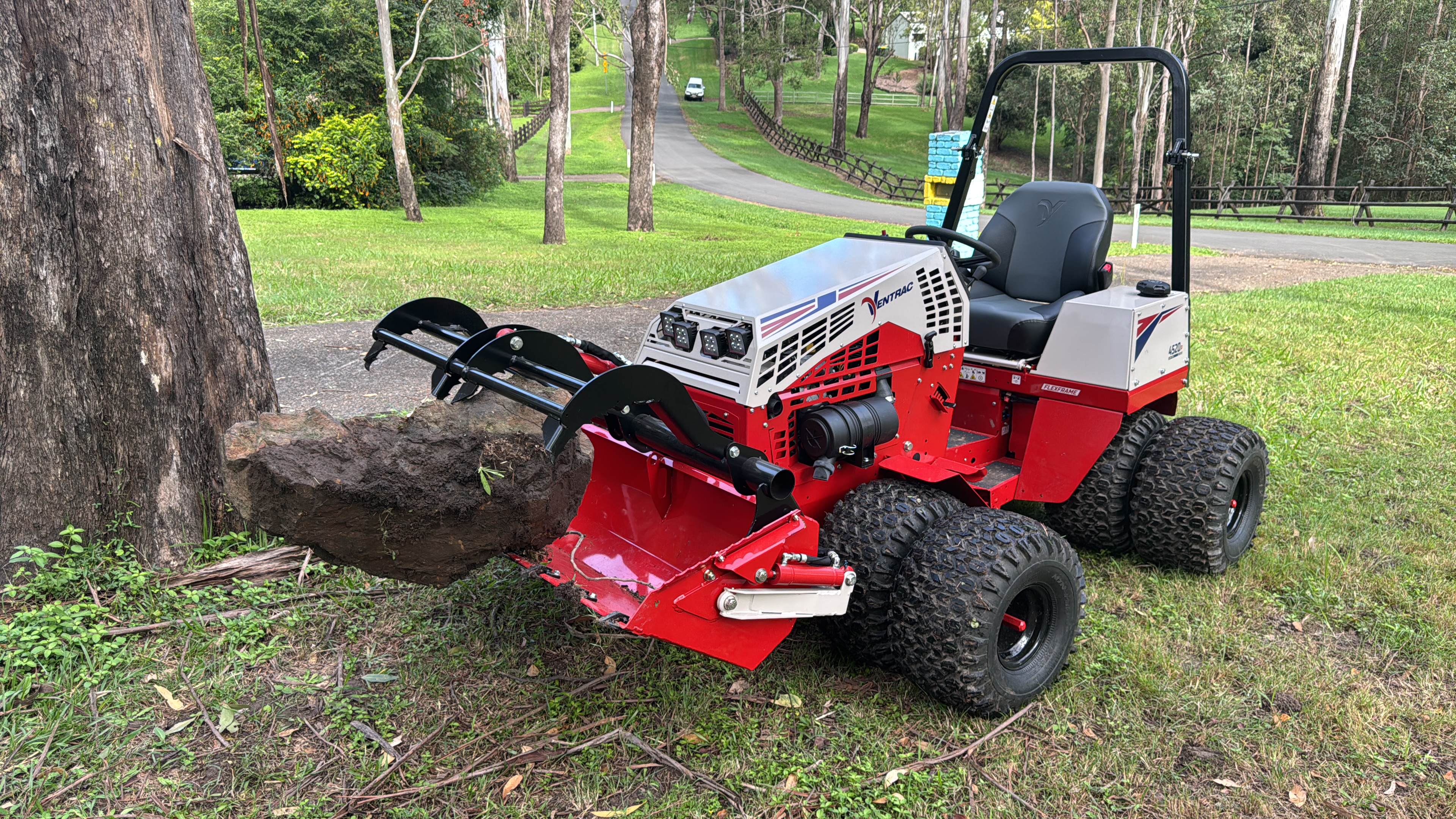 Ventrac 4520P with rock grapple attachment clearing surface rock from a slope, Pullenvale